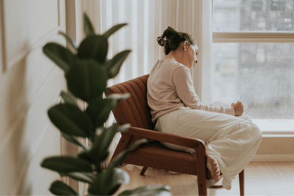 Person sitting by a window journaling, reflecting common anxiety therapy concerns like overthinking, stress, and emotional overwhelm
