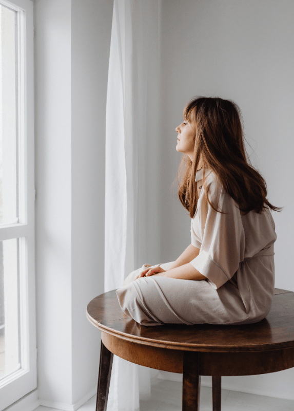 Woman sitting by a window reflecting quietly, representing anxiety therapy support in Voorhees NJ for overthinking and emotional overwhelm